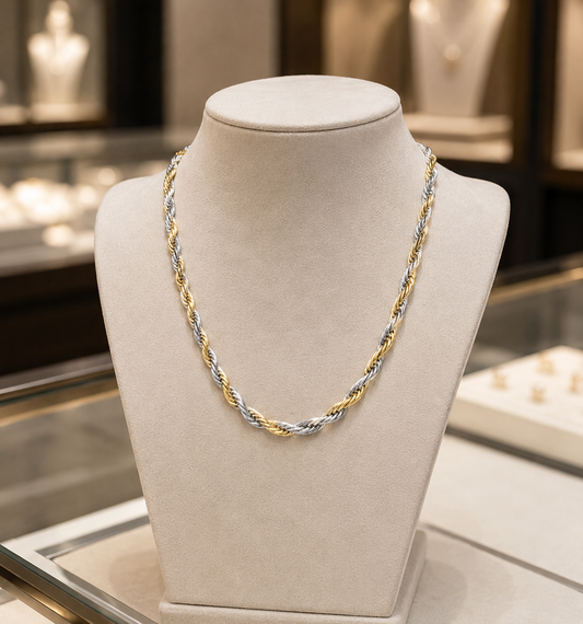 Two-tone gold and silver necklace on a mannequin bust in a jewelry store setting.